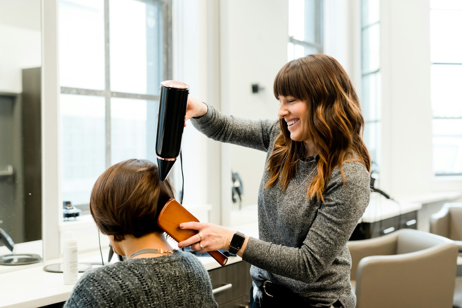 Haarstylist die het haar van een klant in model föhnt